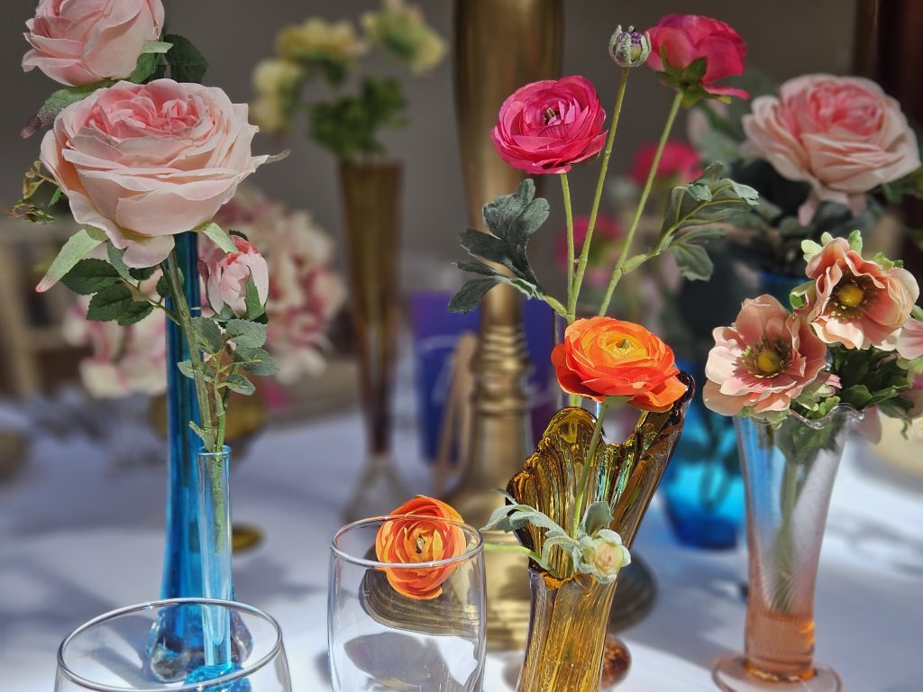 Close up of bright coloured glass vases with a mixture of orange and pink faux flowers